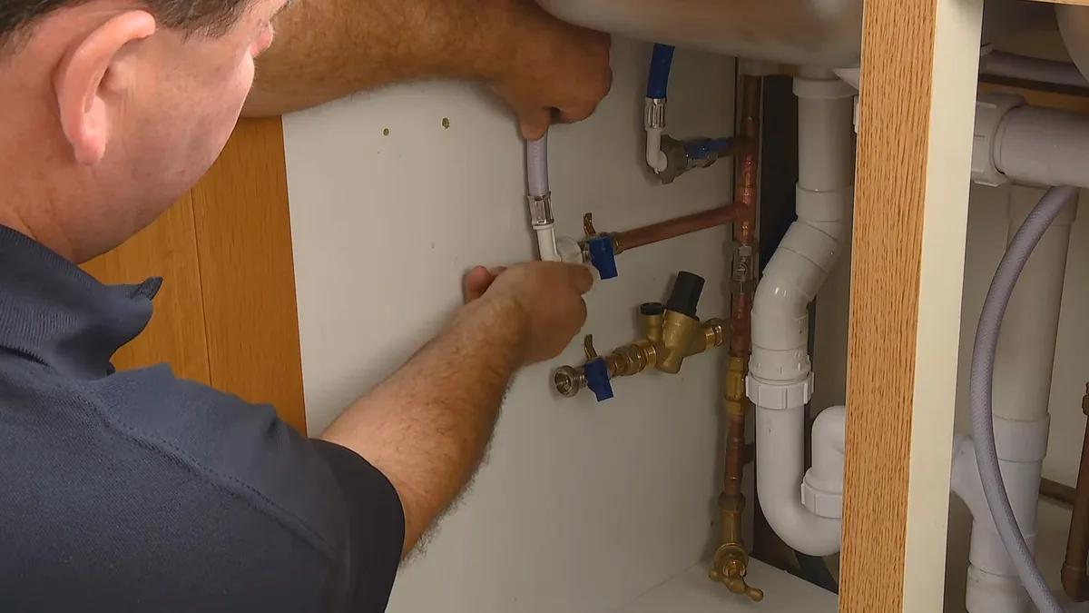 Plumber working on a fixture connection beneath a bathroom sink