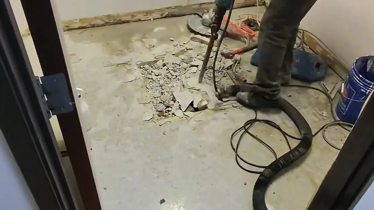 Plumber feeding a drain snake into a clogged household drain line