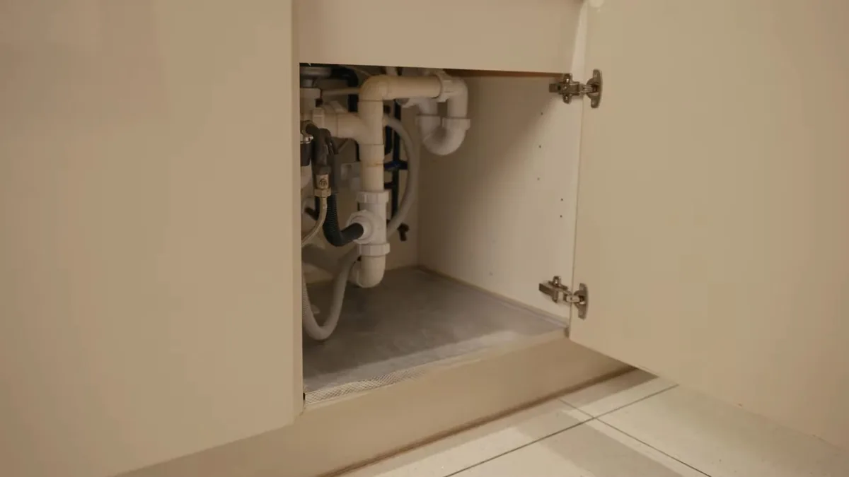 Plumber connecting sink plumbing during a kitchen remodel