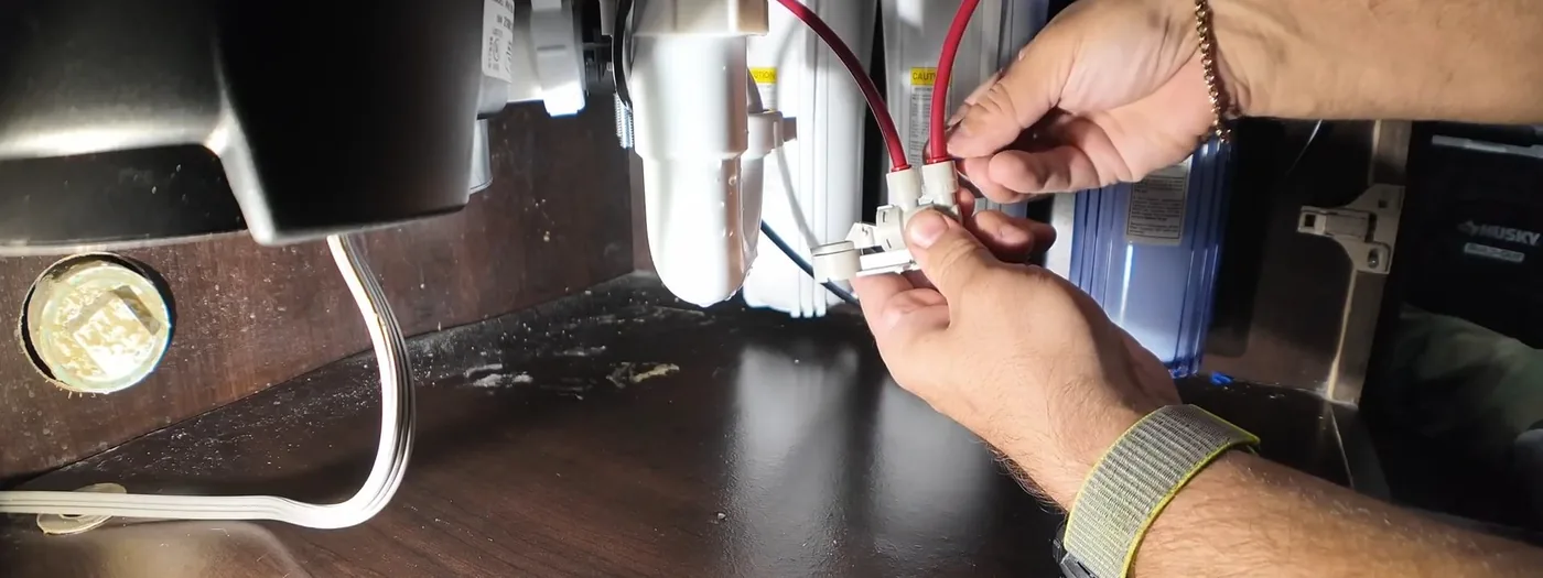 Plumber installing a disposal unit beneath a kitchen sink