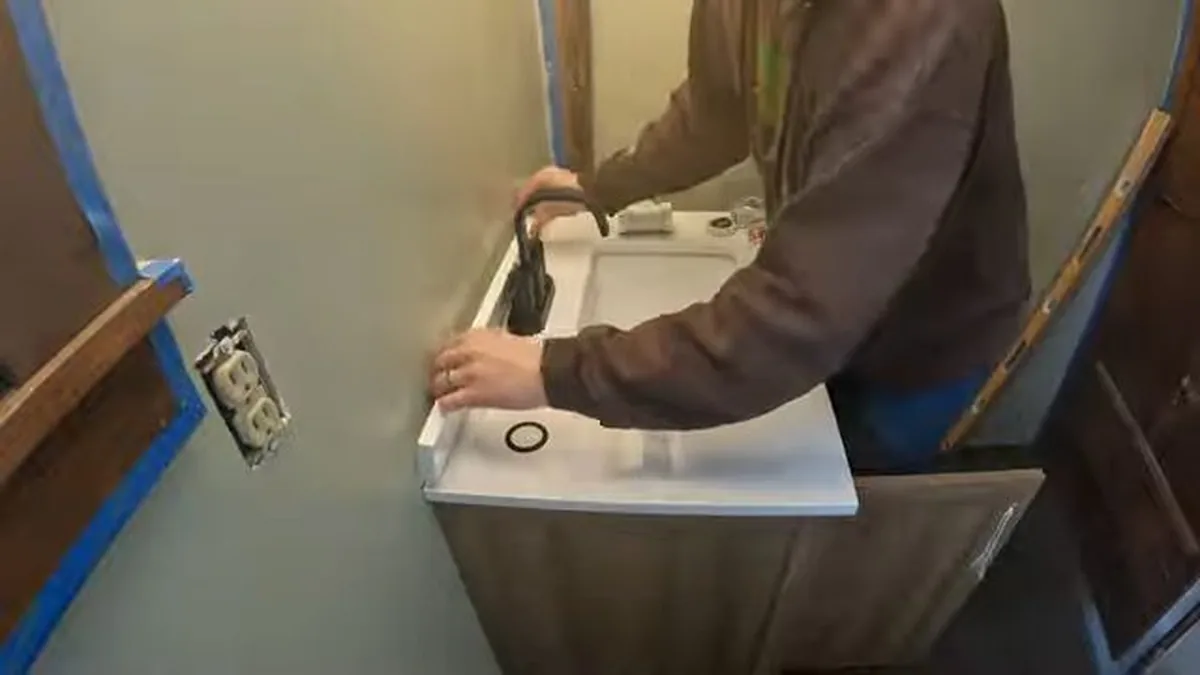 Plumber disassembling a kitchen faucet to repair a leak at the base