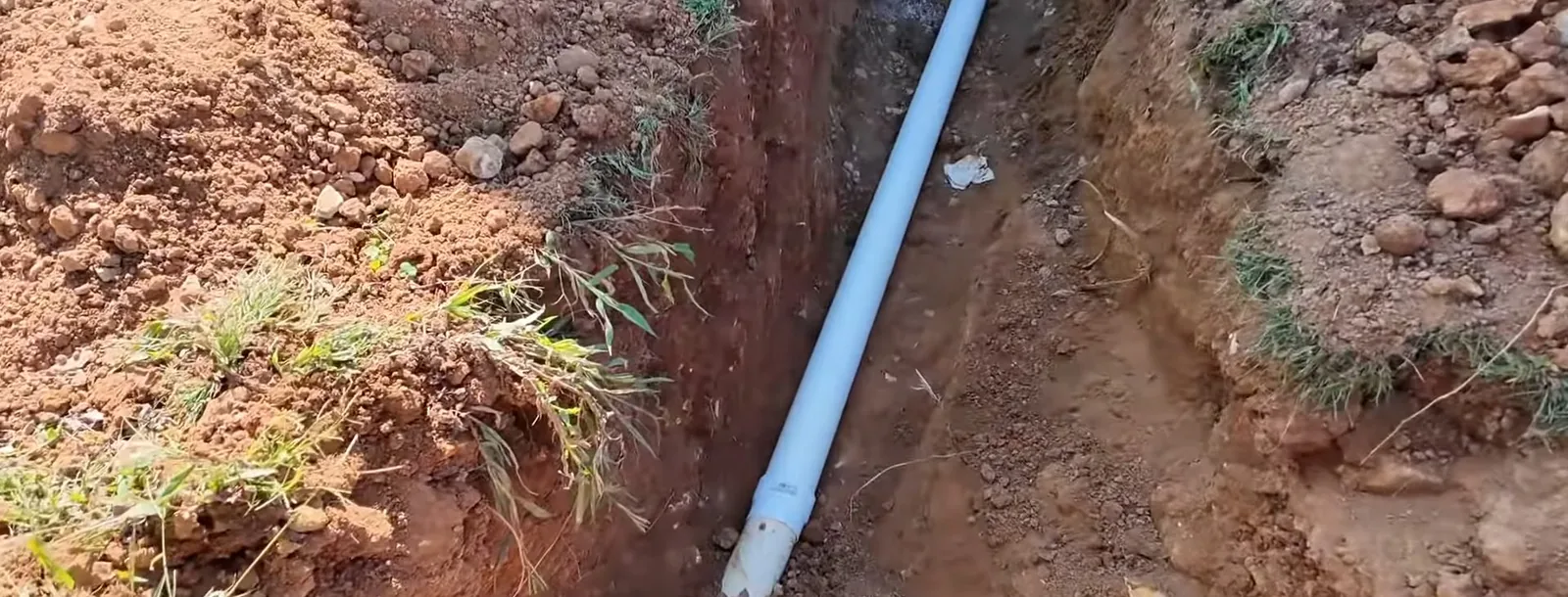 Excavator digging a trench to access a sewer line for replacement