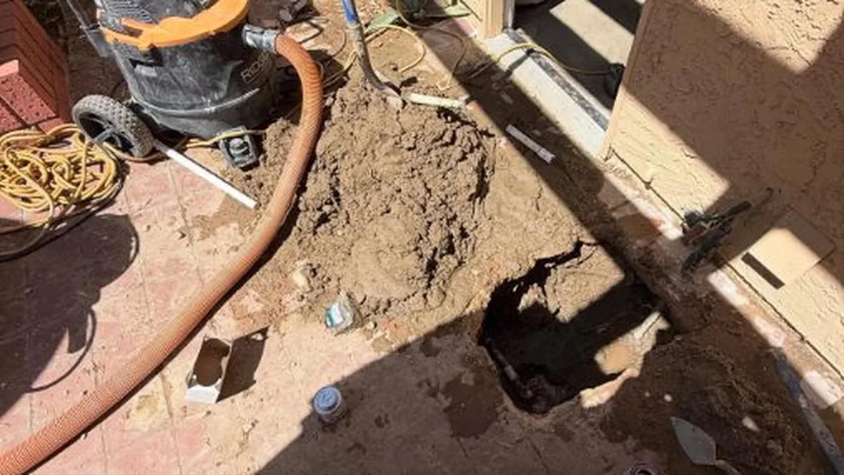 Plumber locating and repairing a slab leak beneath a concrete floor