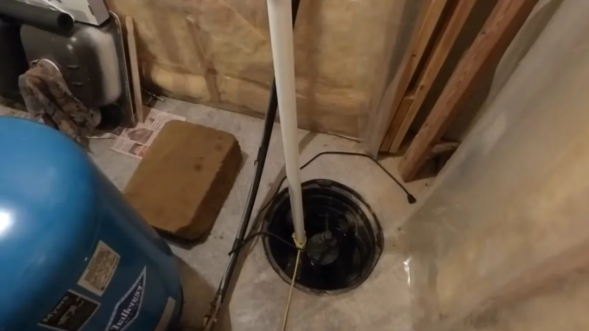 Plumber installing a sump pump into a basement sump basin